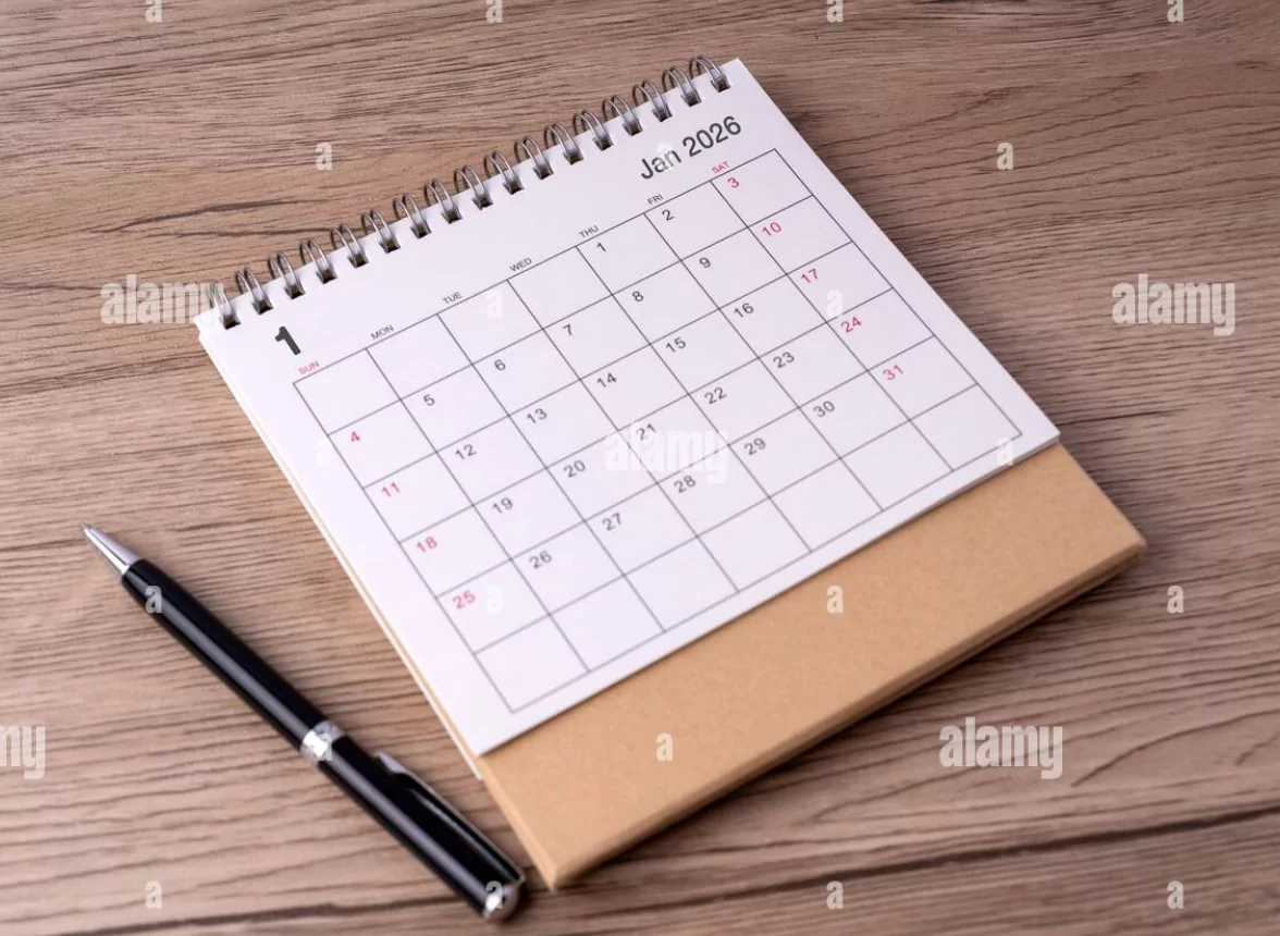 2026 holiday planner on a wooden desk with travel photos and pen